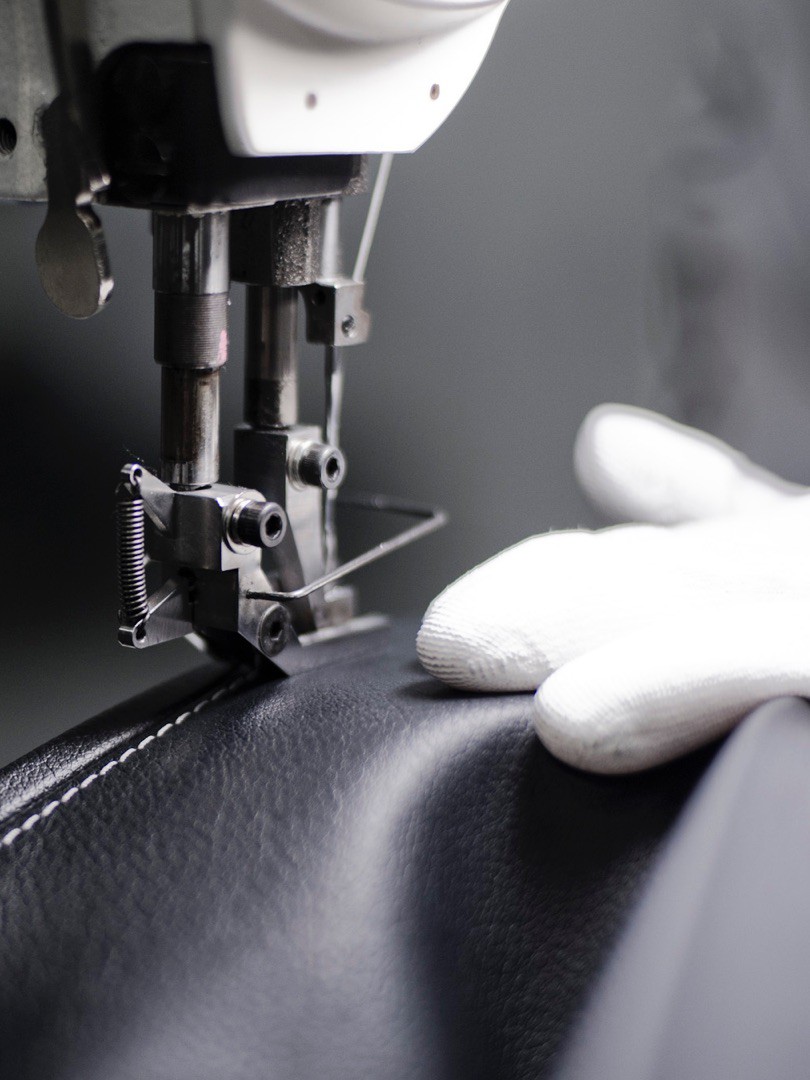 close up of person sewing a Lexus car seat
